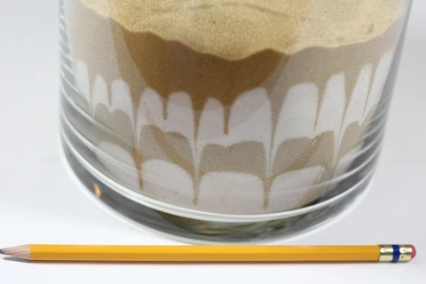 Push the pencil around the outer edge of the vase to create patterns in the sand.